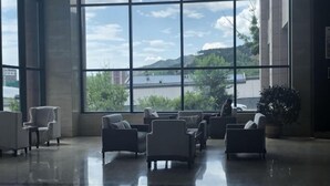 Un vestíbulo amplio con ventanas grandes, varias zonas de estar y una planta en maceta.