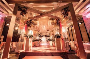 An indoor venue with a central aisle, flanked by rows of chairs, and a decorative archway with hanging elements.