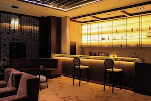 Un área de bar moderna con mostrador, asientos y una pared decorativa.