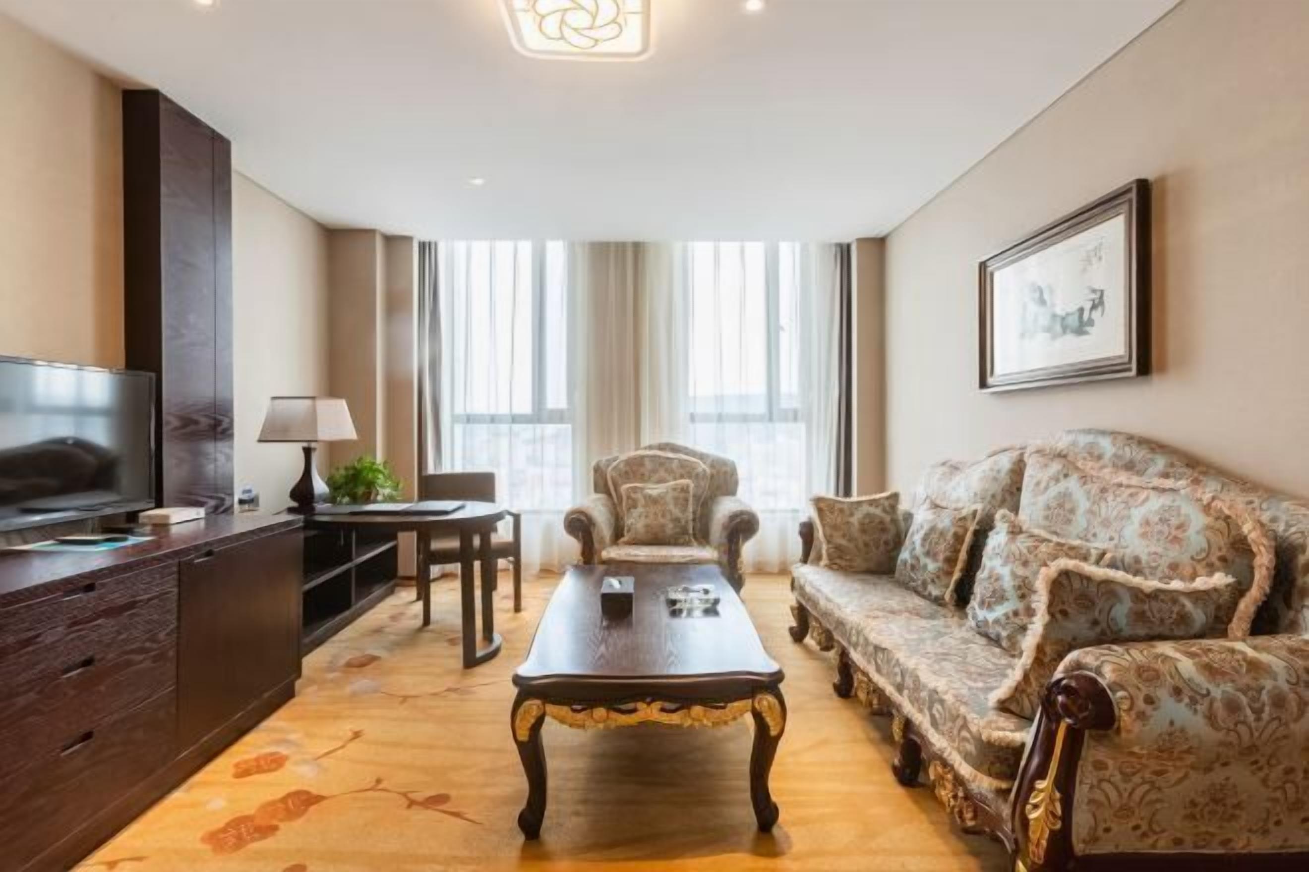 A modern living room with a sofa, armchair, coffee table, TV, and a lamp.