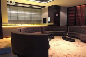 A modern lounge area with a curved sofa, a small coffee table, and a patterned carpet. - Weichang Qianyue Holiday Hotel (Government Branch) (Weichang)