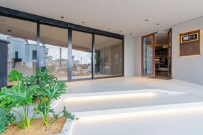 A modern hotel entrance with a glass door, a signboard, and a well-maintained garden area. - Nodo Hotel (Manizales)