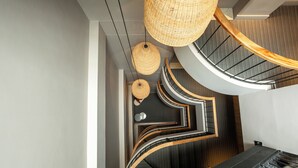 Una escalera moderna con diseño curvo, barandillas de madera y lámparas de fibra.