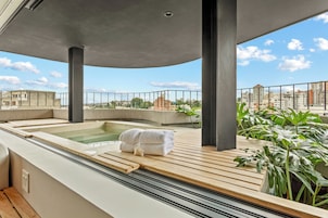A rooftop spa area with a hot tub, wooden deck, and potted plants.