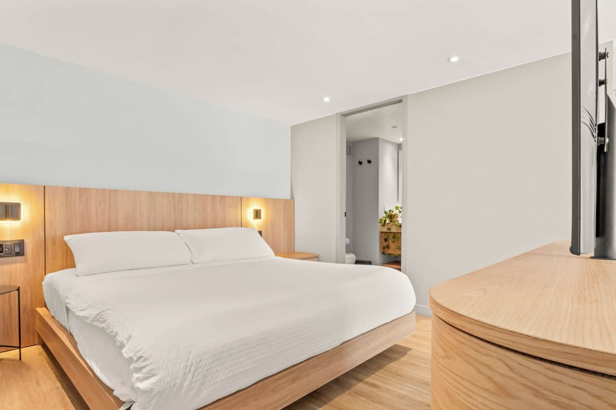 A modern bedroom with a bed, bedside tables, and a built-in TV.