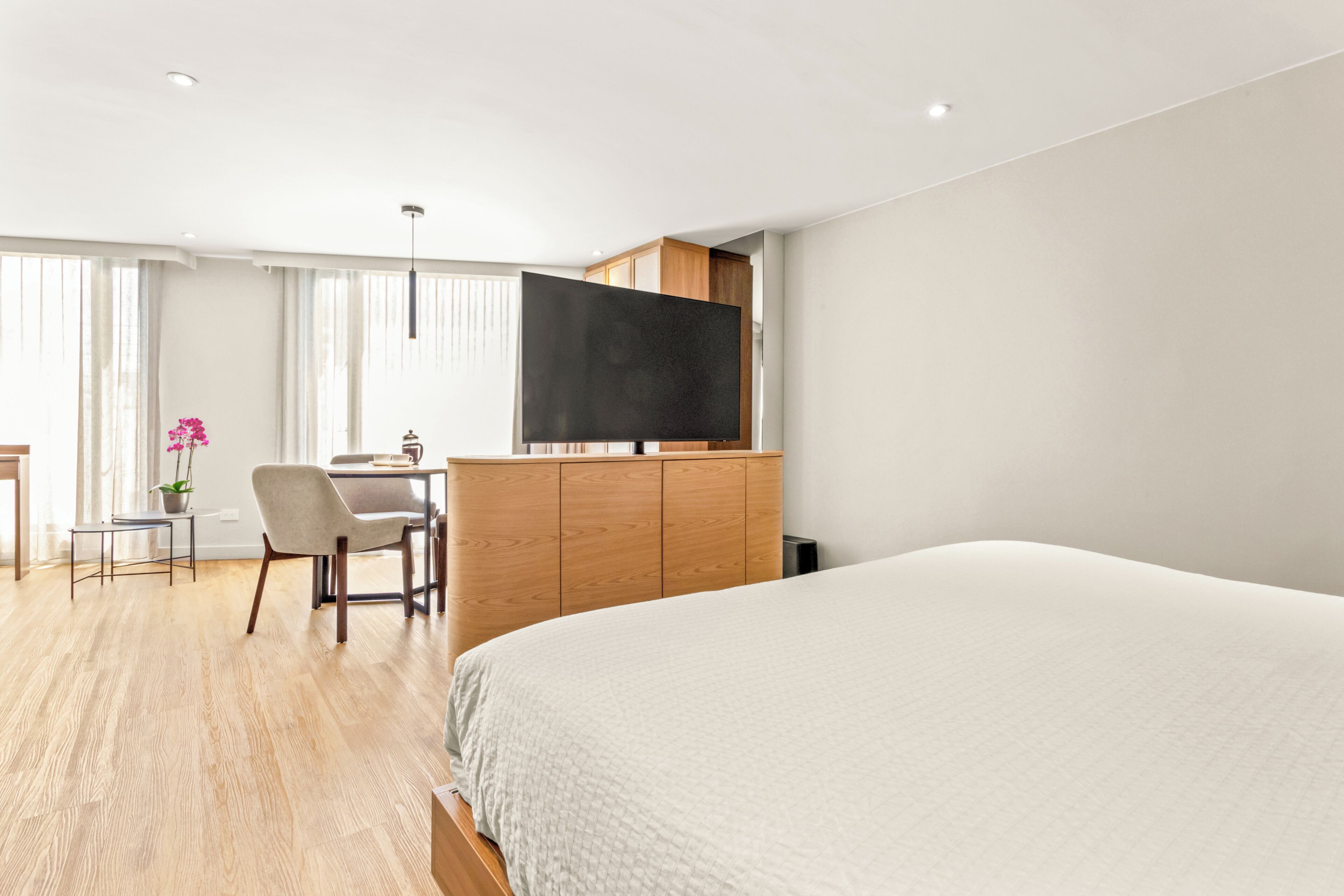 Ein modernes Hotelzimmer mit einem großen Bett, einem Schreibtisch mit Stuhl, einem Flachbildfernseher und einer Topfpflanze.