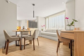 A modern living room with a dining area, a sofa, a coffee table, and a potted plant. - Nodo Hotel (Manizales)