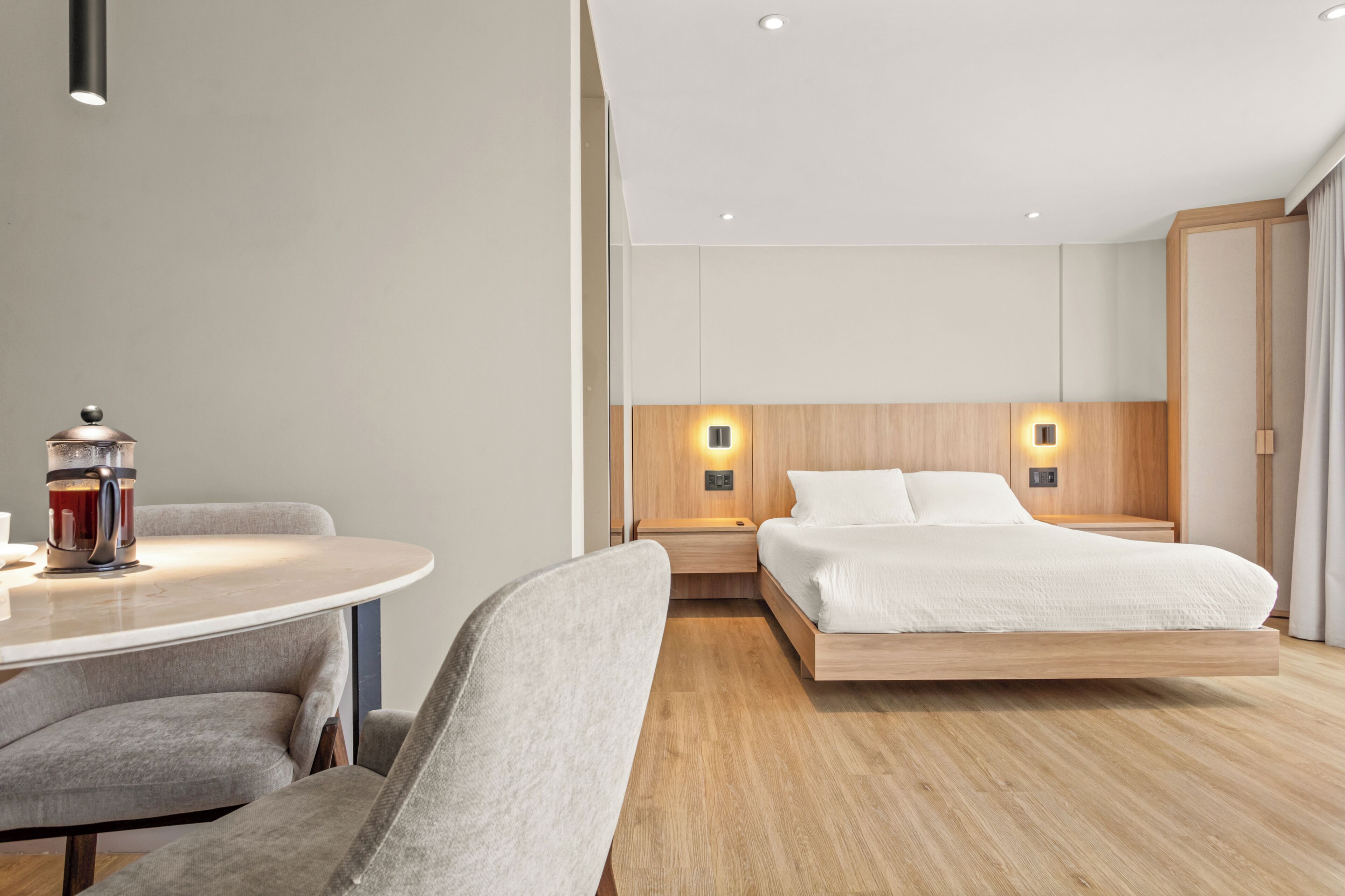 A modern hotel room with a bed, bedside table, and a coffee machine.