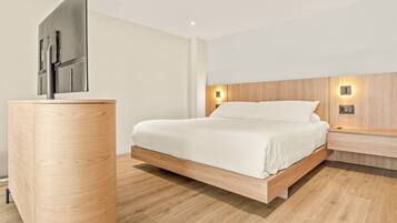 A modern bedroom with a minimalist design, featuring a bed with a wooden frame, a wooden nightstand, a flat-screen TV mounted on the wall, and a wall-mounted light fixture.