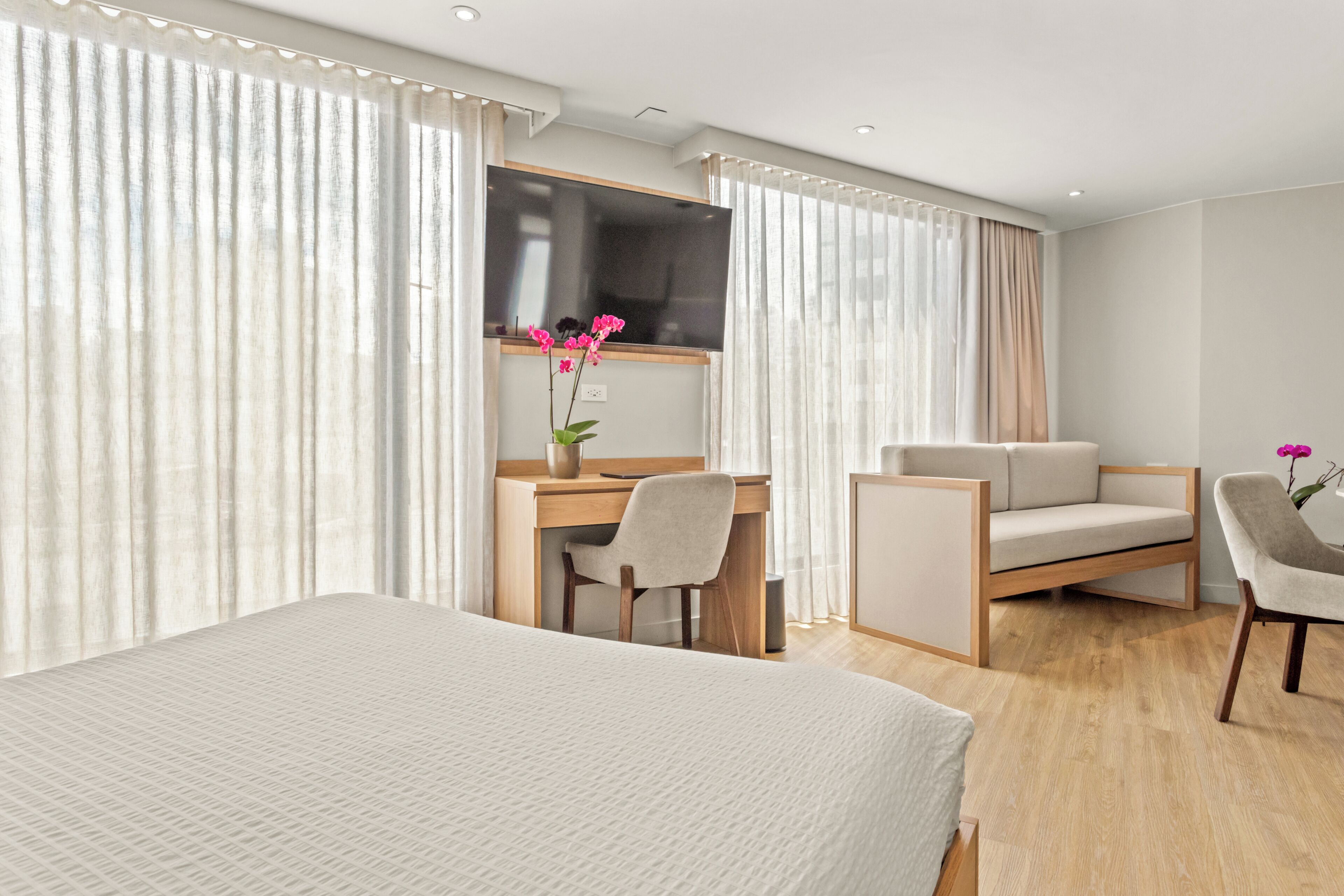 Een hotelkamer met een bed, een bureau, een stoel, een bank en een televisie.