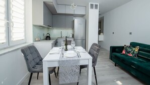 Une cuisine moderne avec un coin repas, des meubles blancs et un canapé vert.