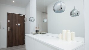 Une salle de bain moderne avec un meuble-lavabo blanc, trois lampes suspendues sphériques et un miroir qui reflète la pièce.