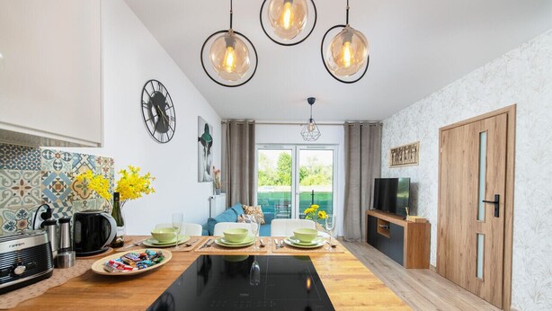 A modern kitchen with a central island, pendant lighting, a clock, and a view to the outdoors. - Poznań Grunwald - Parking & Terrace - by Rentujemy (Poznan)