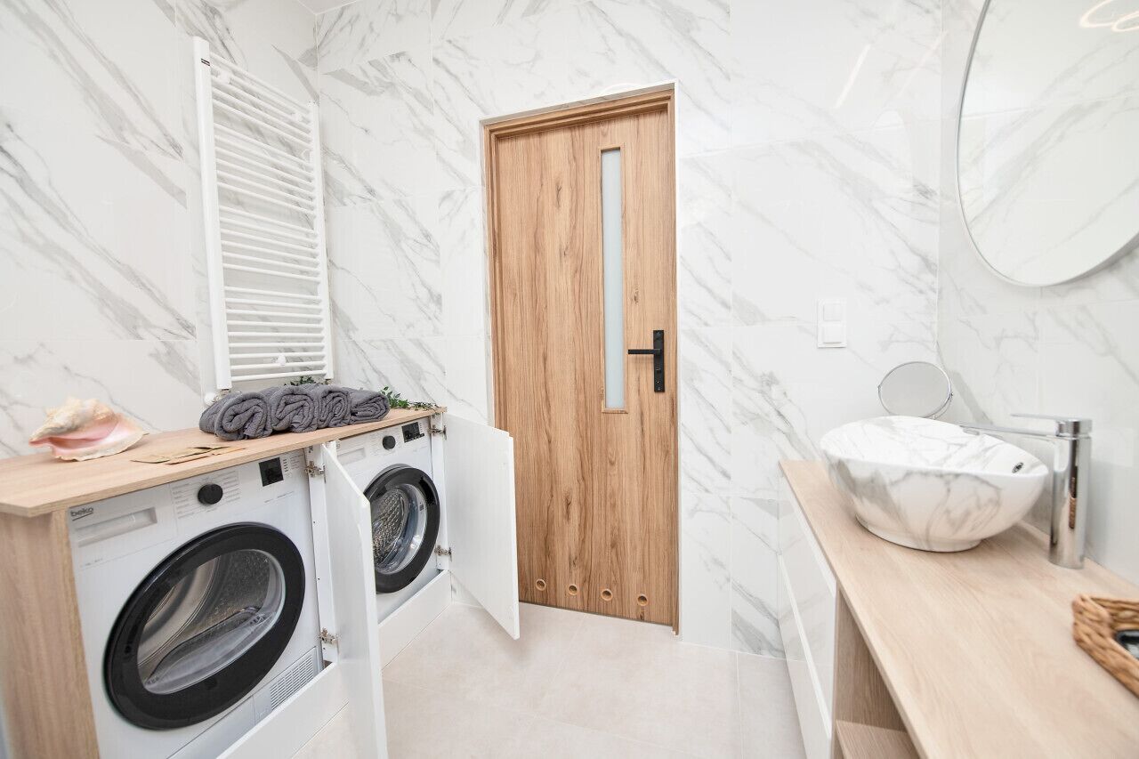A compact laundry area with a washing machine, dryer, and wooden drying rack.