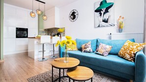A modern living room with a blue sofa, two round wooden tables, and a kitchen in the background. - Poznań Grunwald - Parking & Terrace - by Rentujemy (Poznan)