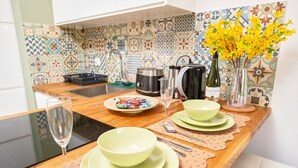 A kitchen with a wooden countertop, a sink, and a tiled backsplash. There are plates, bowls, a wine glass, and a vase with flowers on the counter. - Poznań Grunwald - Parking & Terrace - by Rentujemy (Poznan)