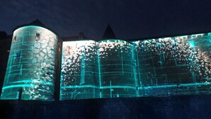 A building with illuminated architectural features, including a curved structure and a tall tower. - Villa Bonne Entente en Ardenne. Château Fort🏰. Nature🍀 Histoire Nautisme Vélo (Donchery)