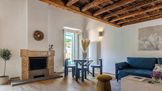 A living room with a fireplace, a sofa, a dining table with chairs, and a view through a door. - Domus Beato Angelico |  two minutes from the Pantheon and Piazza della Minerva (Roma)
