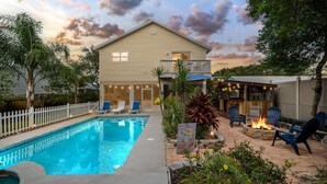 A backyard with a swimming pool, outdoor seating, and a fire pit. - Heated Pool, Spa & Tiki Bar! Full Garage Game Room and Steps Away From The Beach (St. Augustine)
