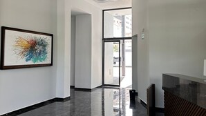 Un moderno hall de hotel con piso de mármol pulido, una recepción y un cuadro abstracto de colores en la pared.