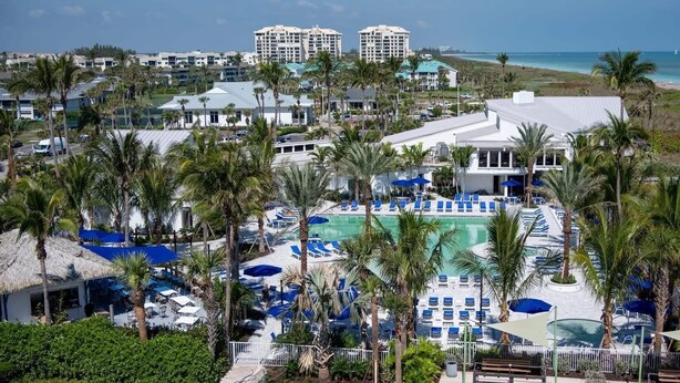 Un complexe hôtelier doté d’une piscine, de palmiers et offrant une vue sur la plage.