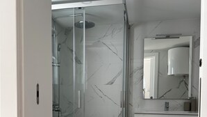Uma casa de banho moderna com cabine de duche em vidro, sanita e lavatório com espelho em cima.