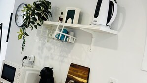 Cozinha moderna com bancada de madeira, pia embutida, micro-ondas, chaleira e um relógio na parede.