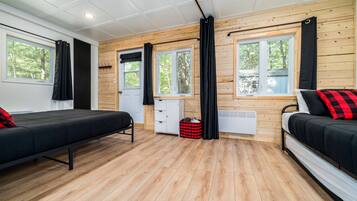 Quarto com duas camas, piso de madeira e grandes janelas com cortinas.
