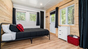 Et soveværelse med en seng, en hvid kommode og et vindue med gardiner.