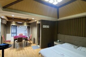A room with a bed, a table with chairs, a window, and a door.