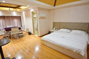 A hotel room with a bed, desk, chair, and a small table.