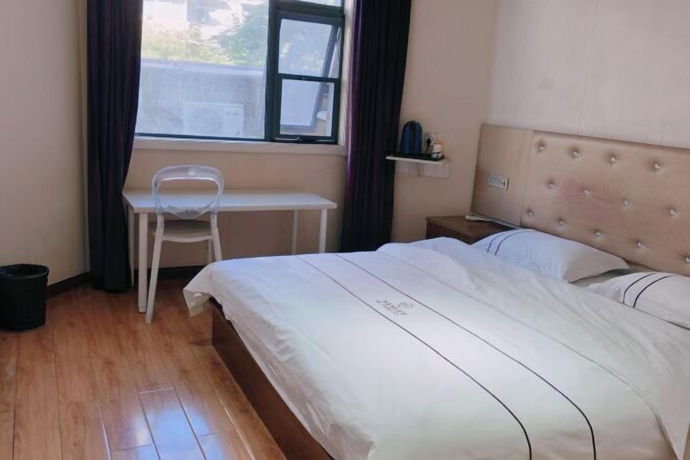 A bedroom with a bed, a desk, and a chair.