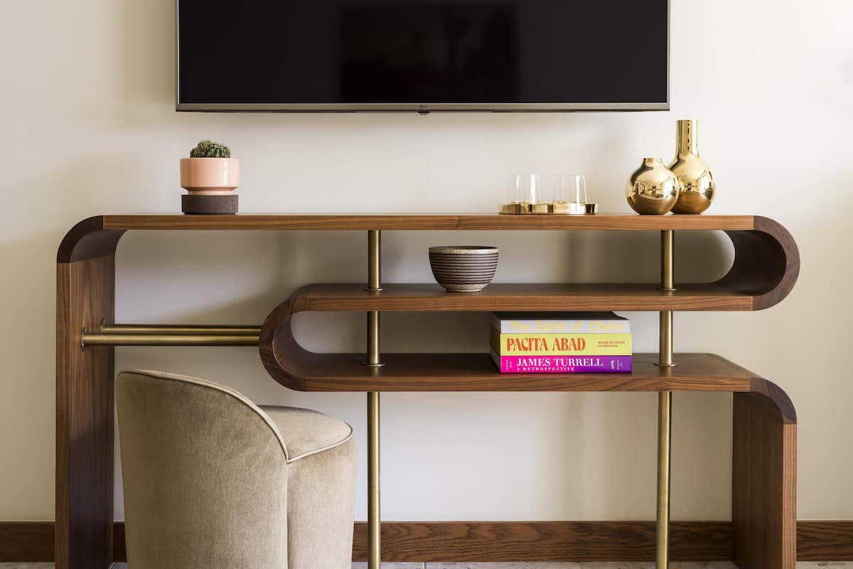 A modern living room with a wooden console table, a flat-screen TV mounted above, and a comfortable armchair.