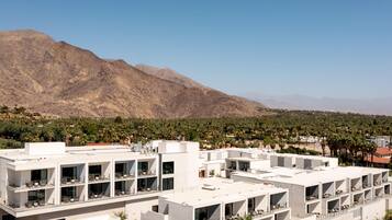 A modern hotel with multiple floors, large windows, and a view of mountains.