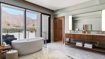 Un baño moderno con una bañera independiente, un tocador de madera y un espejo grande.