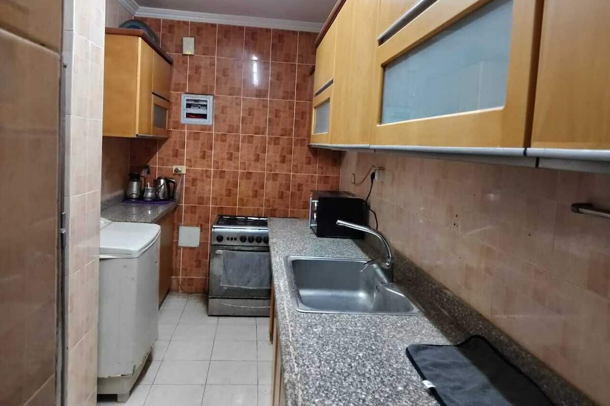 A compact kitchen with a stove, sink, and cabinets.