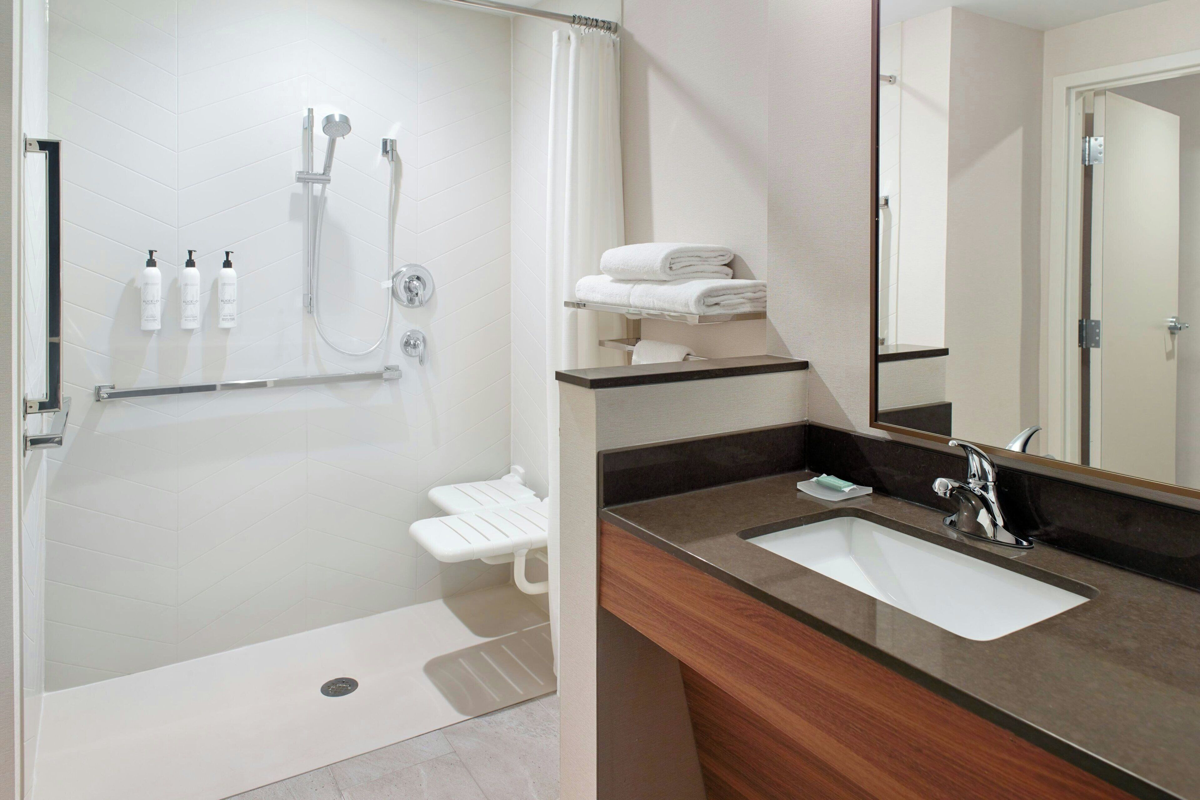 A modern bathroom with a shower, toilet, and sink.