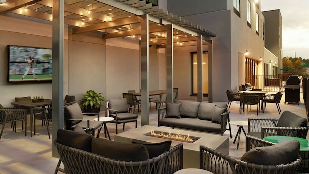 An outdoor patio area with wicker furniture, a flat-screen TV, and a fire feature. - Fairfield By Marriott® Inn & Suites Grovetown (Grovetown)