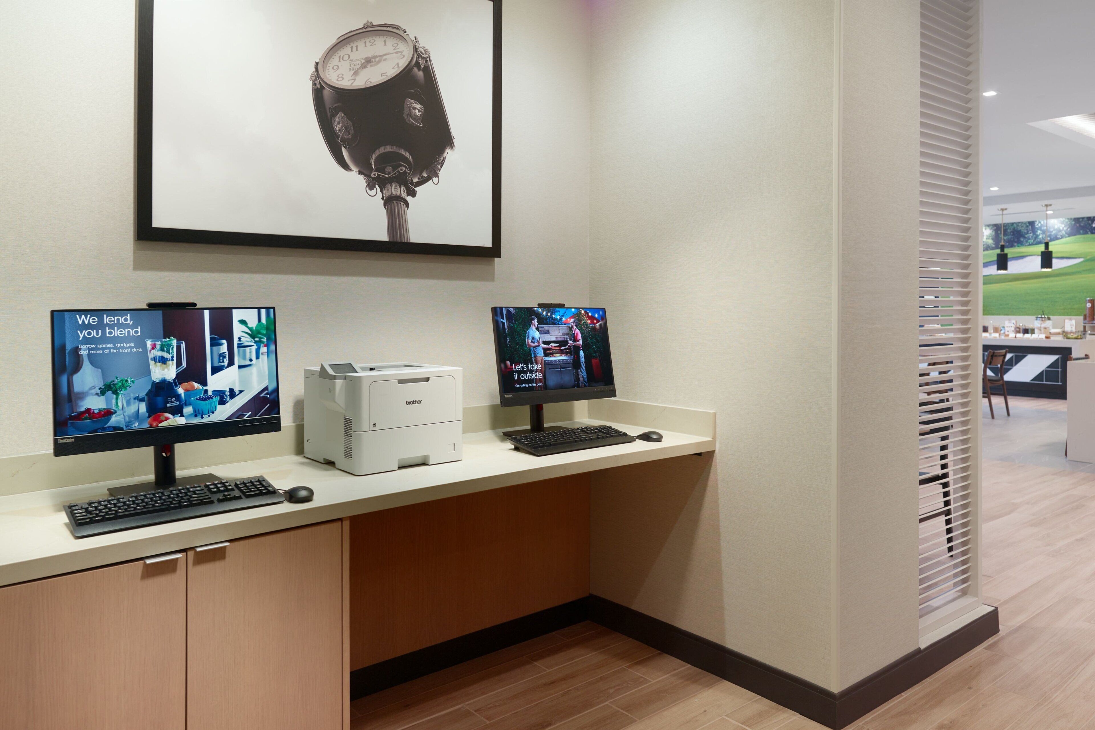A reception desk with two monitors, a printer, and a clock on the wall.