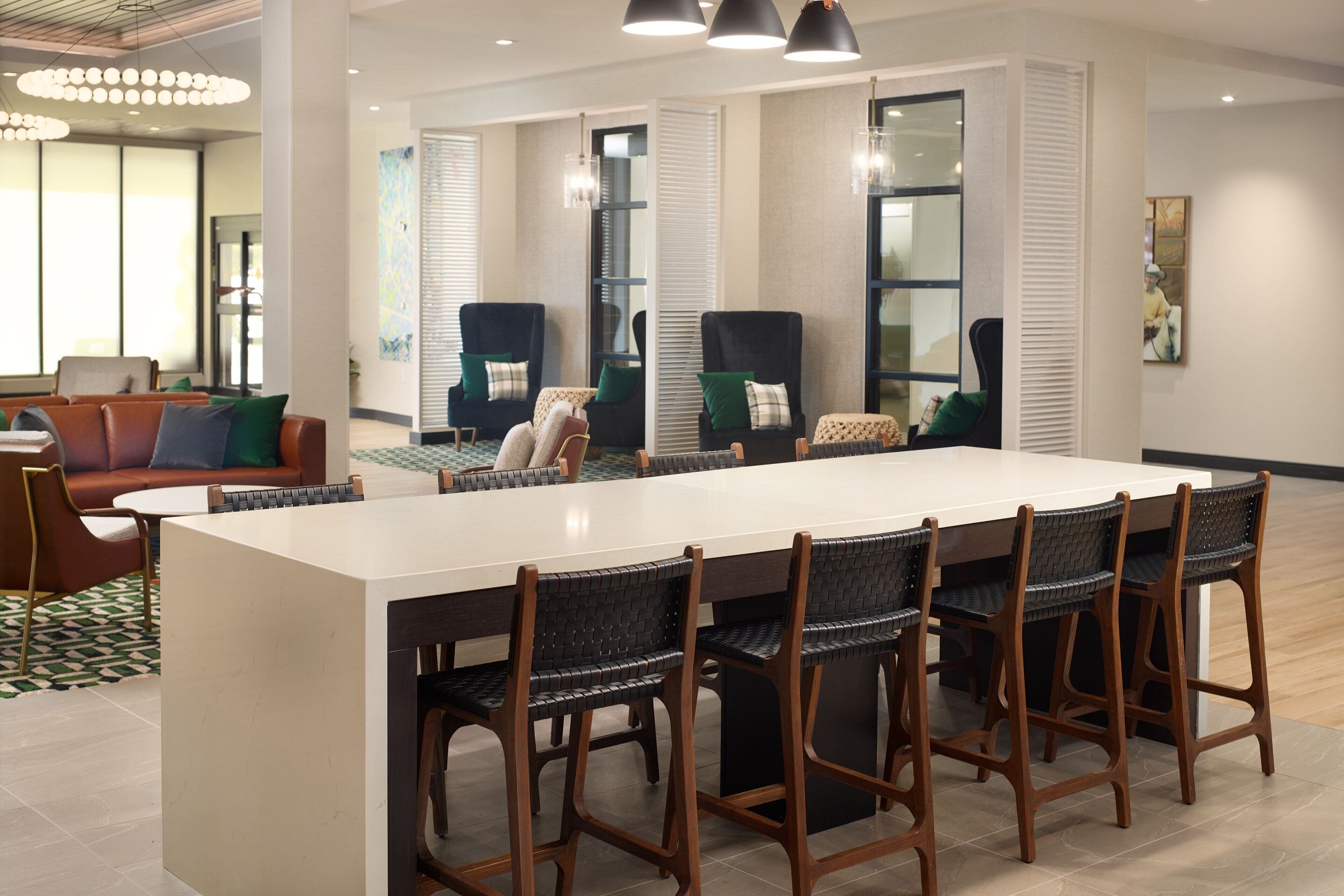 Una cocina moderna con una isla grande, taburetes de bar y un área de comedor con sofá y sillas.