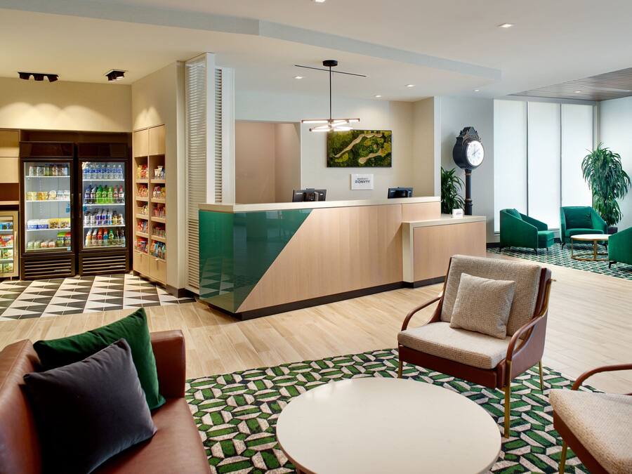 A hotel lobby with a reception desk, seating area, and a refreshment kiosk.