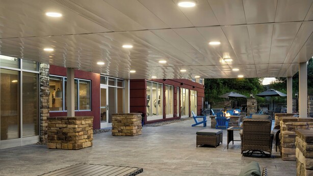 An outdoor patio area with stone pillars, wicker furniture, and a fire feature. - Fairfield By Marriott® Inn & Suites Beckley (Beckley)