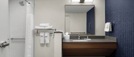 Ein modernes Badezimmer mit Dusche, Waschbecken und Spiegel.