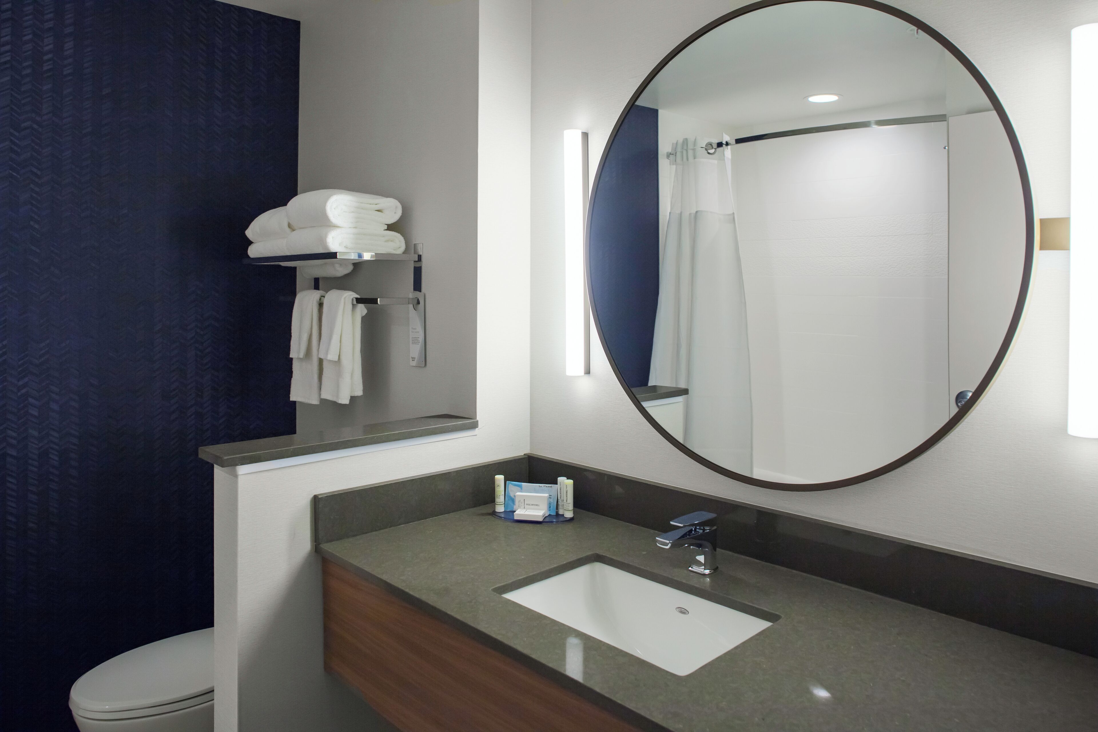 Une salle de bain moderne avec un grand miroir, un lavabo et des toilettes.