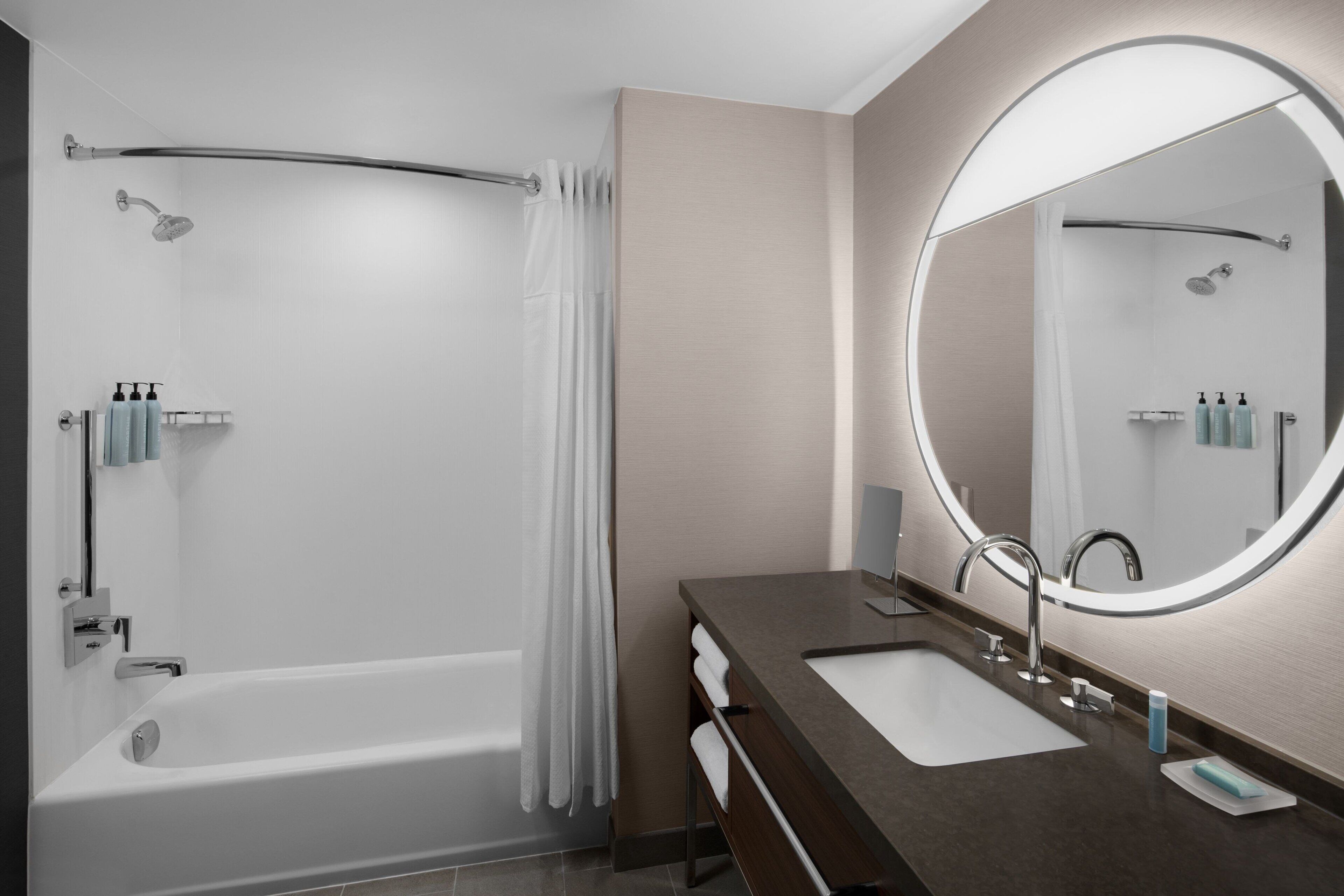 A modern bathroom with a bathtub, a vanity with a mirror, and a shower area.