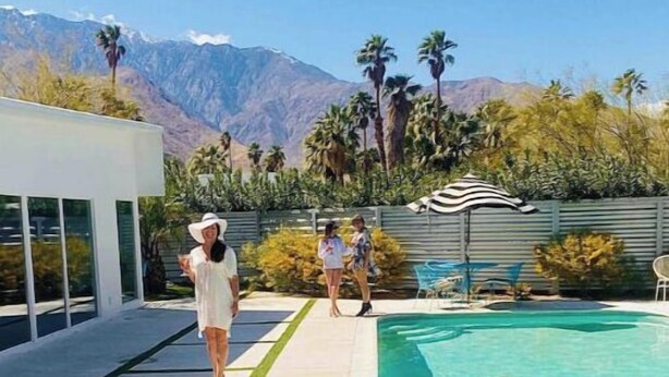 A poolside area with lounge chairs, a pool, and a view of mountains.