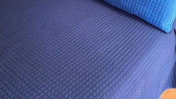 Una cama con una colcha azul acolchada y dos almohadas a juego.