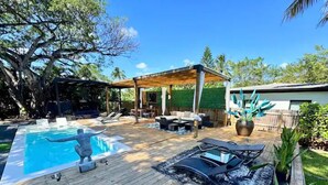 A wooden deck with a swimming pool, lounge chairs, and a covered seating area. - Tree House (Fort Lauderdale)