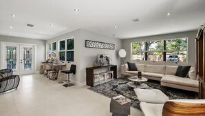 A spacious living room with a sofa, coffee table, and a dining area with chairs and a table. - Tree House (Fort Lauderdale)