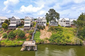 Uma propriedade à beira-mar com várias casas brancas, um cais e uma escadaria que dá acesso às casas.